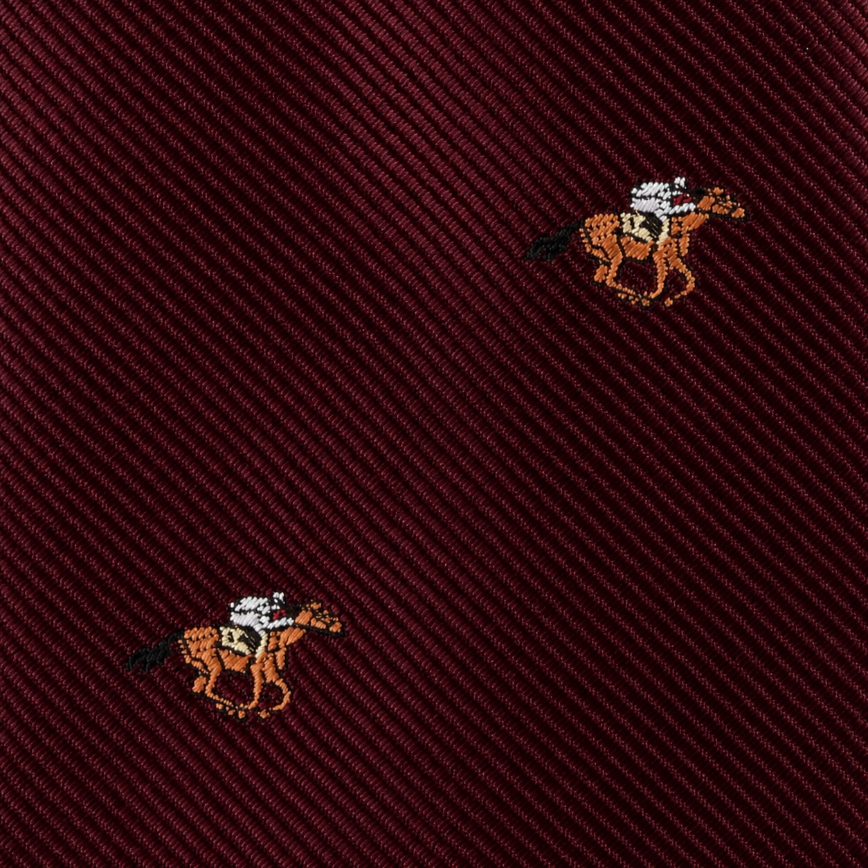 Close-up of the Horse Racing Skinny MAROON Tie, featuring a diagonal ribbed texture and small embroidered horse and jockey motifs—perfect for horse racing enthusiasts and equestrian style.