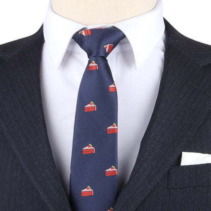 A person wearing a dark pinstripe suit, white dress shirt, and a Strawberry Cake Skinny Tie in navy blue with a red cake slice pattern.