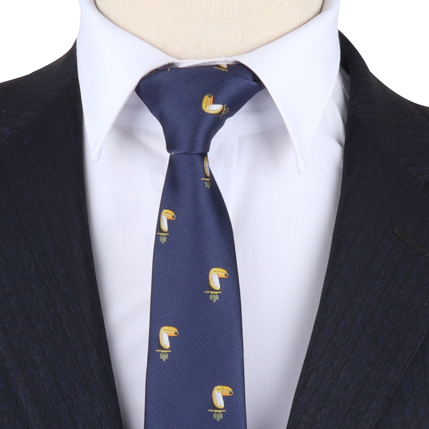A person wearing a dark pinstripe suit and white dress shirt pairs it with the Toucan Bird Skinny Tie—featuring a blue tropical toucan pattern, making it a unique gift for bird lovers.