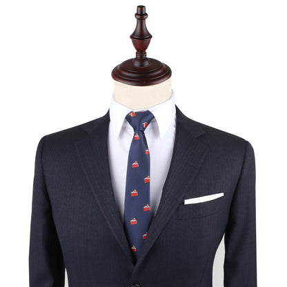 A mannequin dressed in a dark pinstripe suit, white dress shirt, Strawberry Cake Skinny Tie featuring playful dessert prints, and a white pocket square.