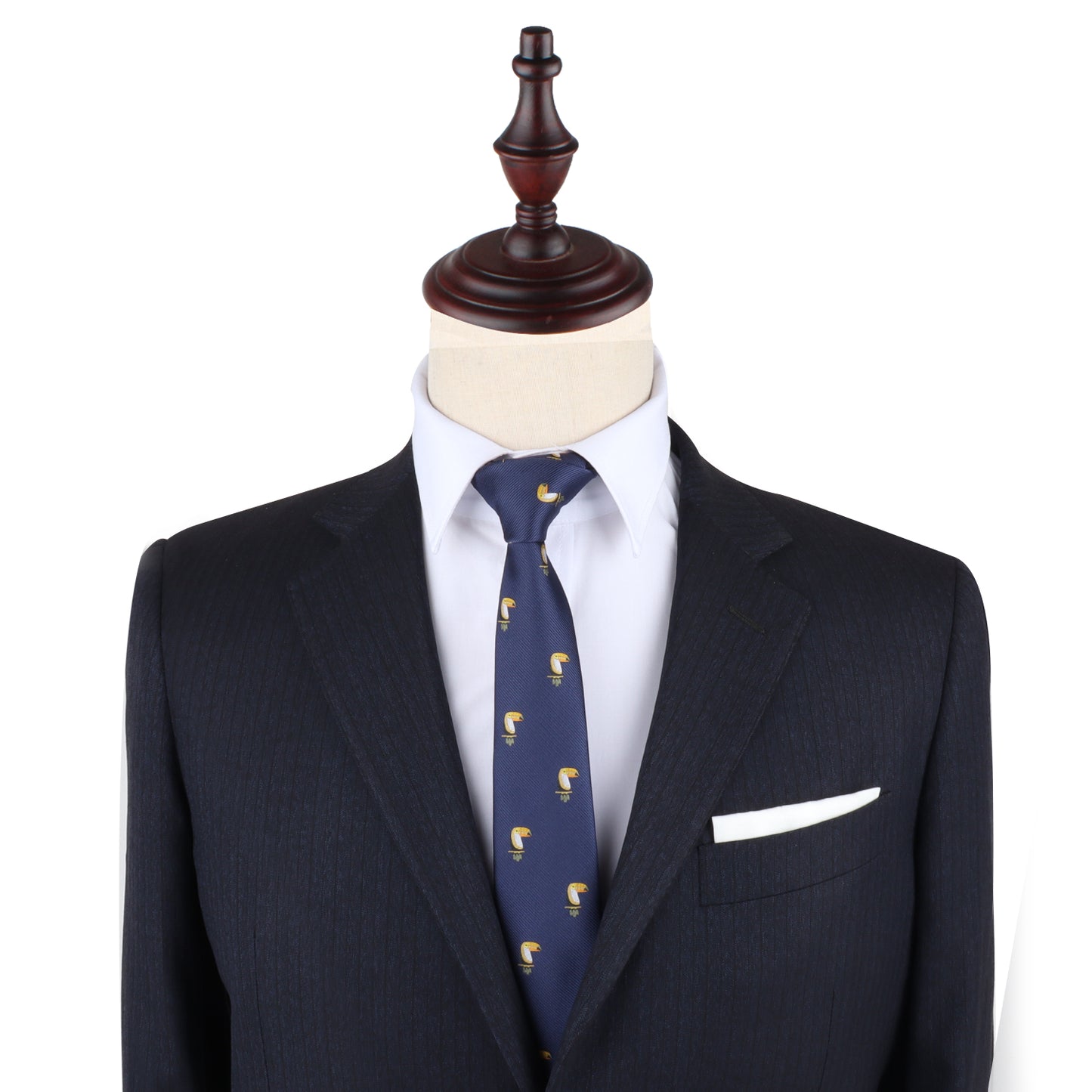 A dark suit jacket, white dress shirt, and Toucan Bird Skinny Tie are displayed on a mannequin with a wooden stand; a white pocket square adds flair—making this tie a perfect unique gift for bird lovers.