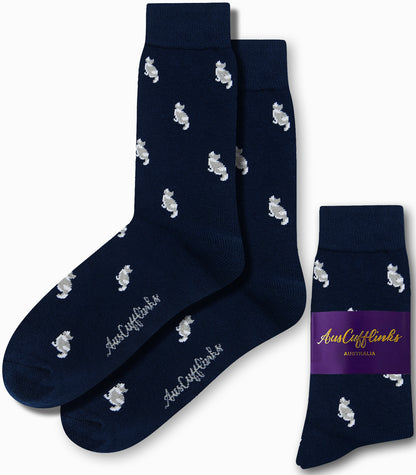 These foot-friendly accessories, known as Cat Socks, feature a small white cat pattern on navy blue with "AusCufflinks" branding on the side. They offer playful charm in packaging that is purple and gold.