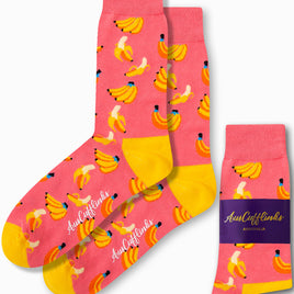 Banana Pink Socks, featuring a playful pattern of bananas in tropical hues with yellow heels and toes, displayed alongside their packaging.