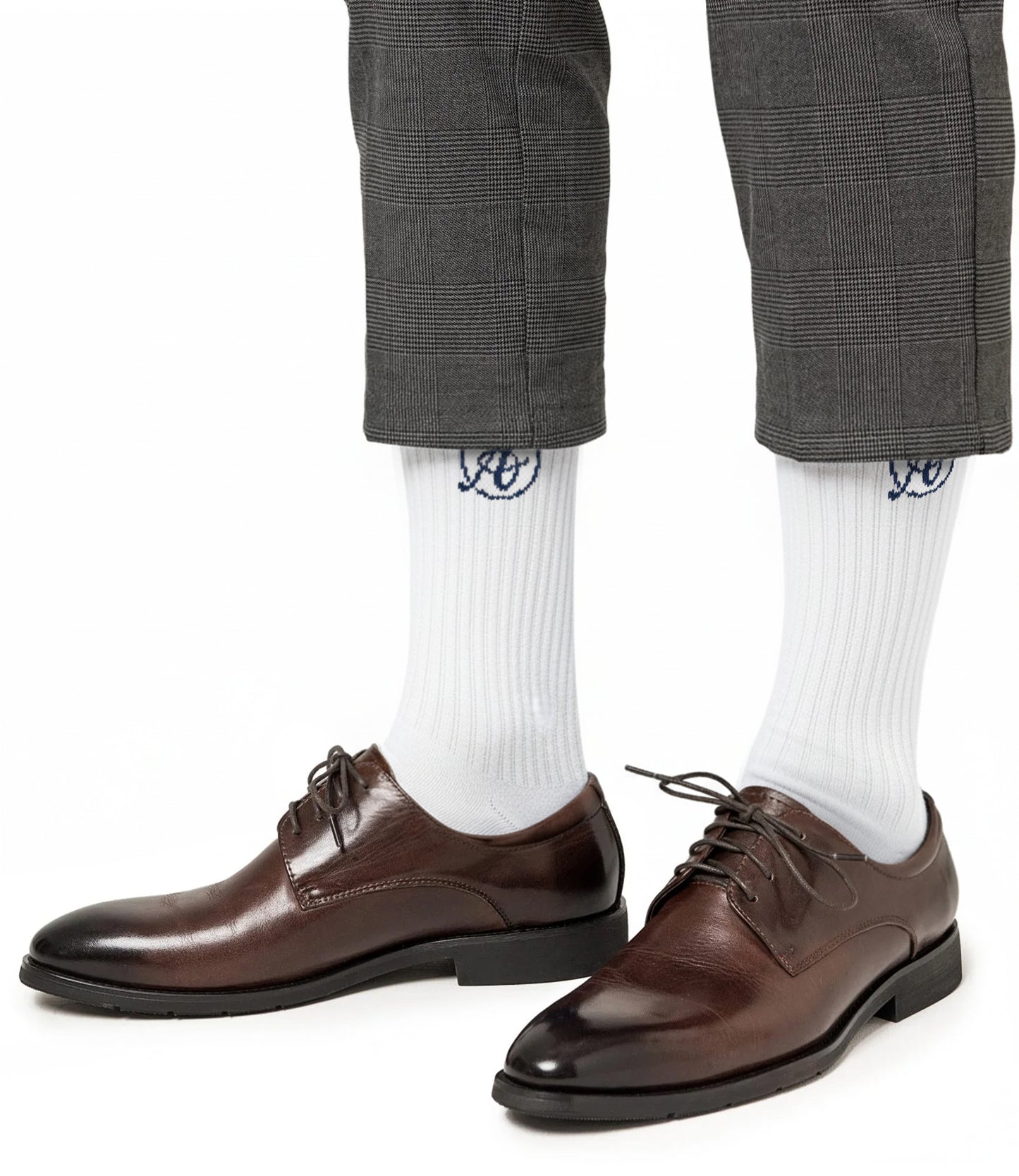 A person wearing brown leather dress shoes, gray plaid cropped pants, and AusCufflinks Socks—white cotton blend with a blue logo.