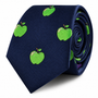 The Apple Skinny Tie showcases a navy blue background decorated with a lively green apple print, offering a playful yet stylish accent to any ensemble.