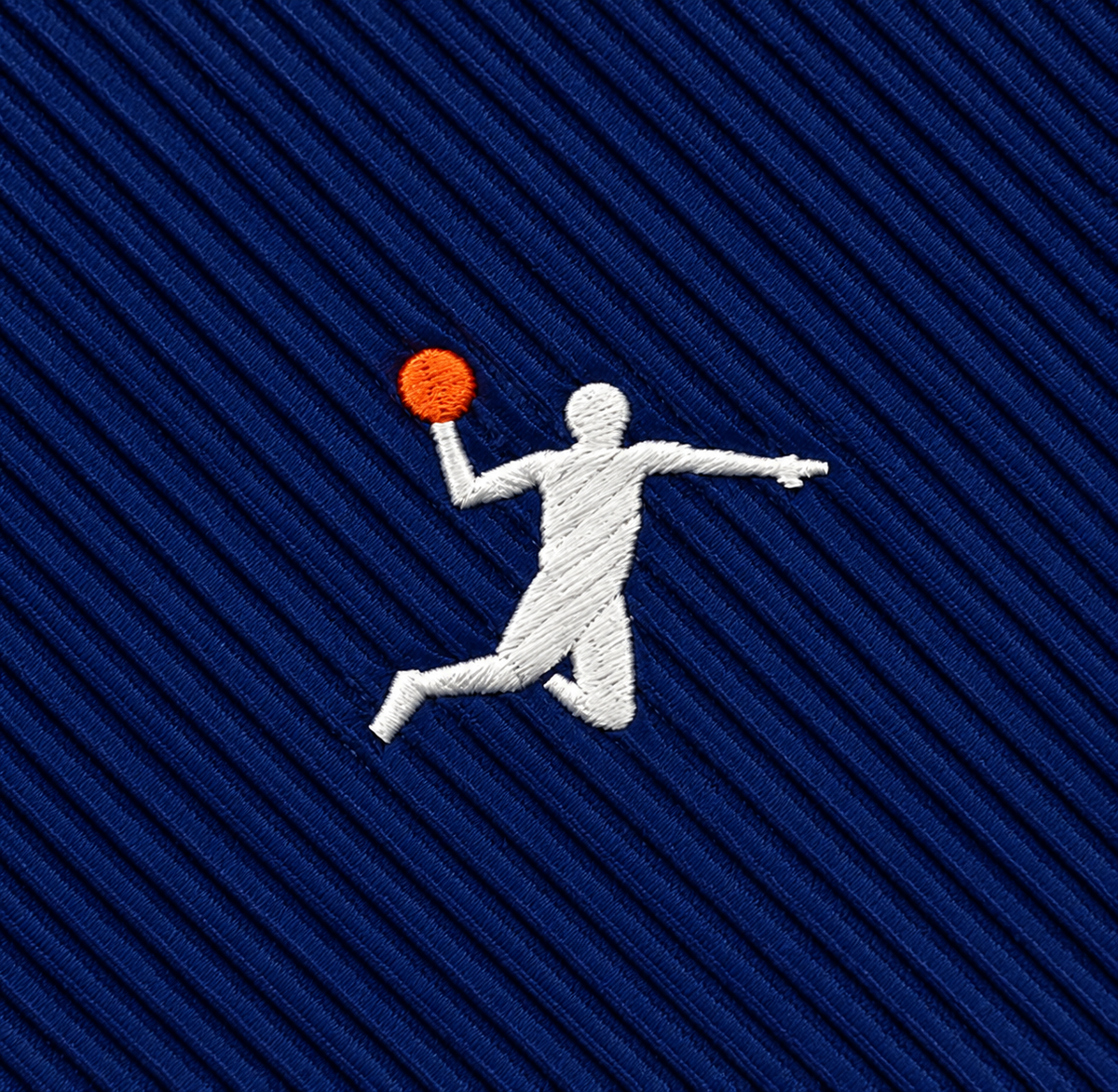 Embroidered on blue textured fabric, the Basketball Dunk Skinny Tie features a white silhouette of a person holding an orange ball mid-jump in a dynamic slam dunk pose—an energetic design perfect for basketball enthusiasts.