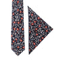 The Black Red Orange Amaryllis Cotton Floral Skinny Tie & Pocket Square Set features a captivating red and white floral pattern on a pristine white backdrop, adding an air of dark allure.