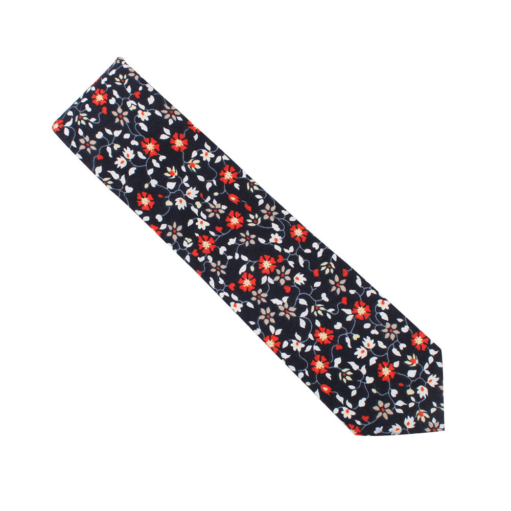 The Black Red Orange Amaryllis Cotton Floral Skinny Tie & Pocket Square Set, featuring a black tie embellished with red and white Amaryllis-inspired blooms intertwined with lush green leaves, exudes dark allure.