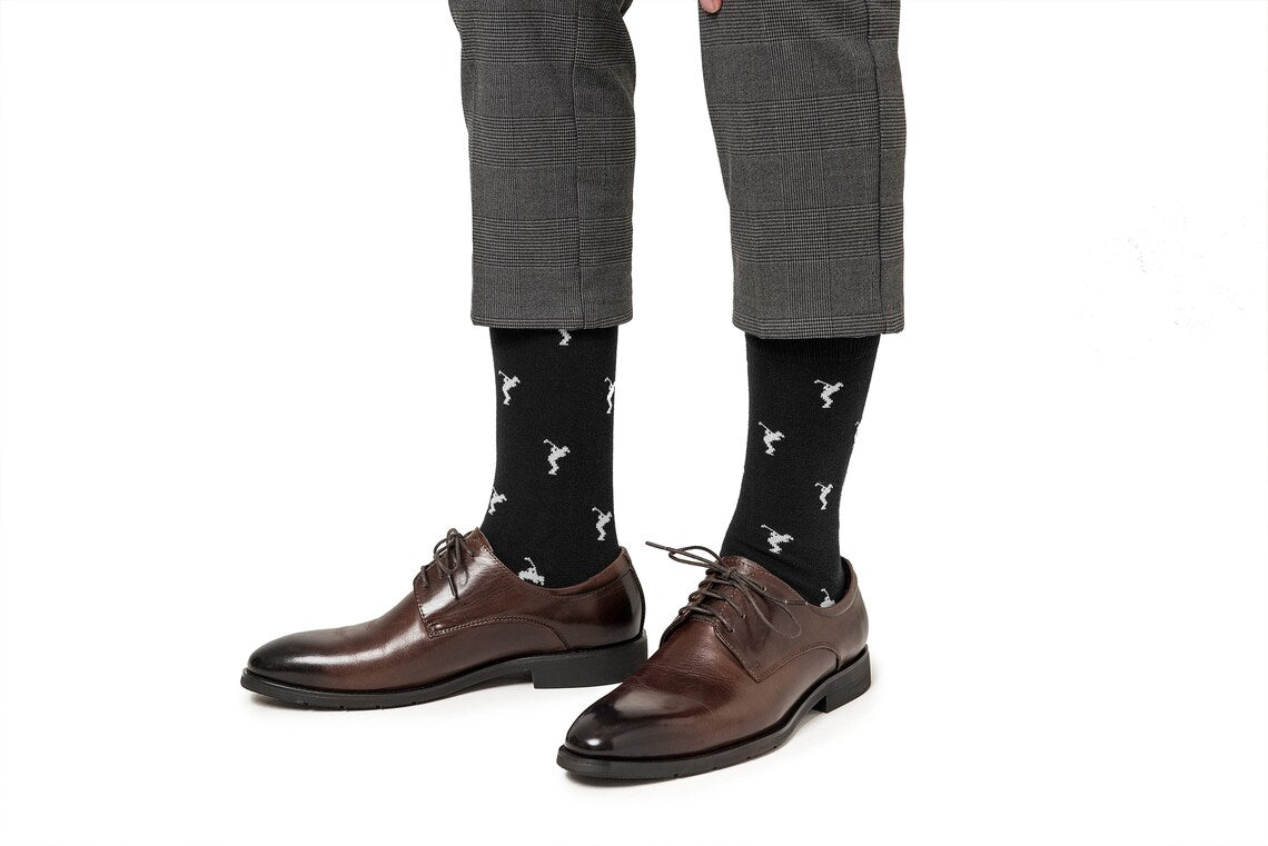 Person wearing brown dress shoes, gray plaid dress pants with ankles exposed, and Golf Swing Black Socks featuring a white pattern—a perfect golf gift for the stylish enthusiast.