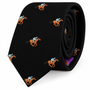 The Horse Racing Skinny BLACK Tie features a repeating pattern of orange jockeys riding horses on a sleek black background, shown rolled up to highlight its unique design—a standout accessory for horse racing enthusiasts and style connoisseurs.