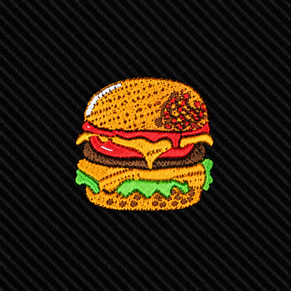 Introducing the Black Tie Burger: an embroidered patch featuring a cheeseburger with lettuce, tomato, cheese, and a sesame seed bun on a dark, textured background—an ideal gift for food lovers and the perfect quirky accessory for men’s fashion enthusiasts.