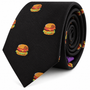 Introducing the Black Tie Burger: a black necktie adorned with a repeating pattern of small embroidered hamburgers, displayed rolled up on a white background—an ideal gift for food lovers and a standout choice for those seeking quirky men’s fashion.