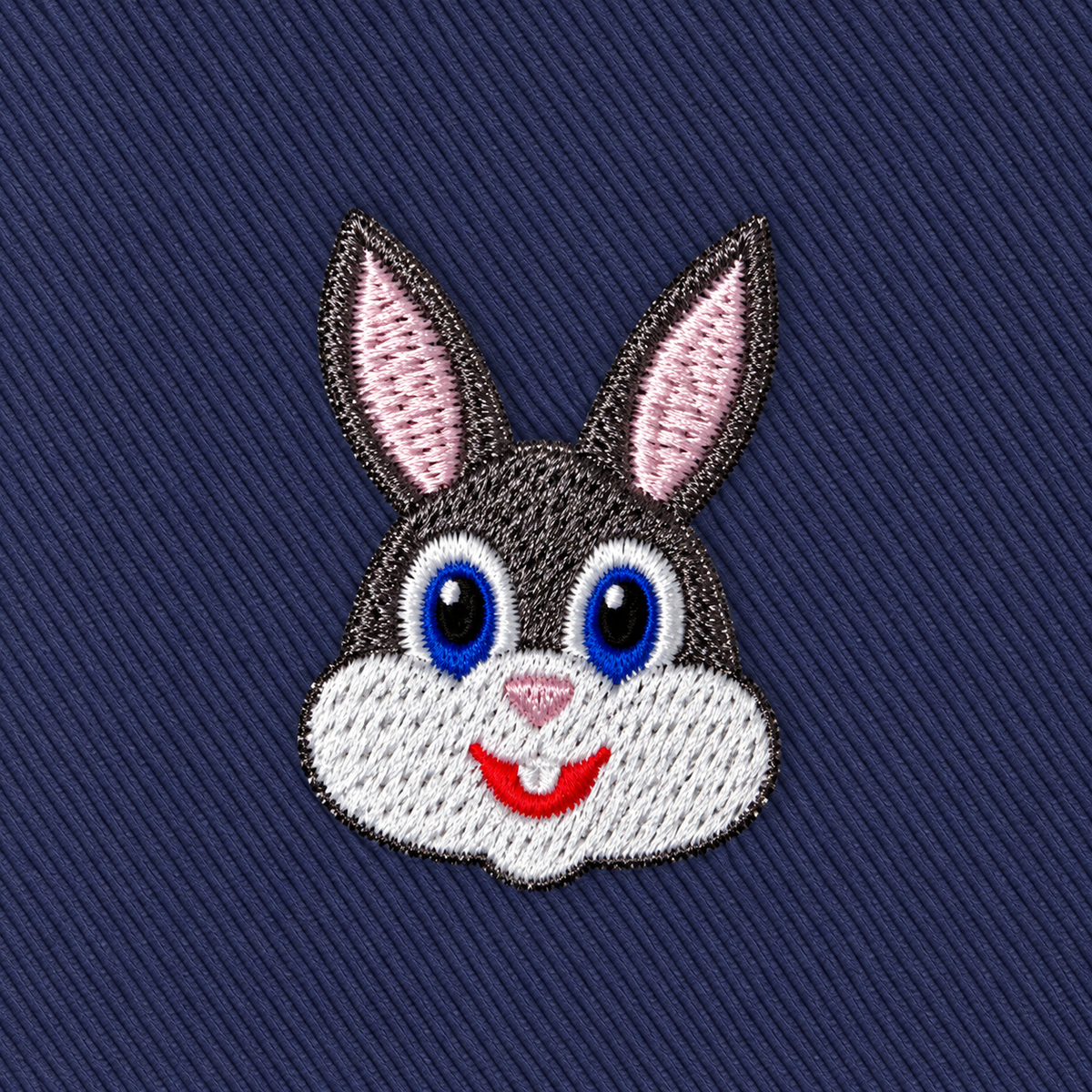 The Bunny Skinny Tie features an embroidered cartoon rabbit face with blue and brown eyes, gray and white fur, and pink inner ears on a dark blue fabric background—perfect for adding playful charm to any animal print or novelty tie collection.