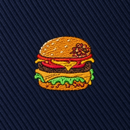 Add a playful touch to your wardrobe with the Burger Skinny Tie, featuring an embroidered patch of a cheeseburger with lettuce, tomato, cheese, and a sesame seed bun on dark blue textured fabric—a perfect foodie gift or quirky accent for any burger lover.