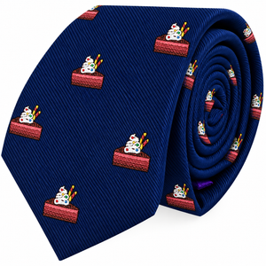 The Cake Skinny Tie is a blue novelty accessory featuring a repeating pattern of chocolate cake slices topped with whipped cream and candles, making it perfect for anyone who wants to add a fun dessert-themed touch to their outfit.