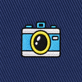 The Camera Skinny Tie features an embroidered patch of a blue and white camera with a yellow lens, stitched onto a dark blue diagonal-striped fabric—an ideal photography-themed accent for your necktie collection or a unique gift for photographers.