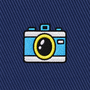 The Camera Skinny Tie features an embroidered patch of a blue and white camera with a yellow lens, stitched onto a dark blue diagonal-striped fabric—an ideal photography-themed accent for your necktie collection or a unique gift for photographers.
