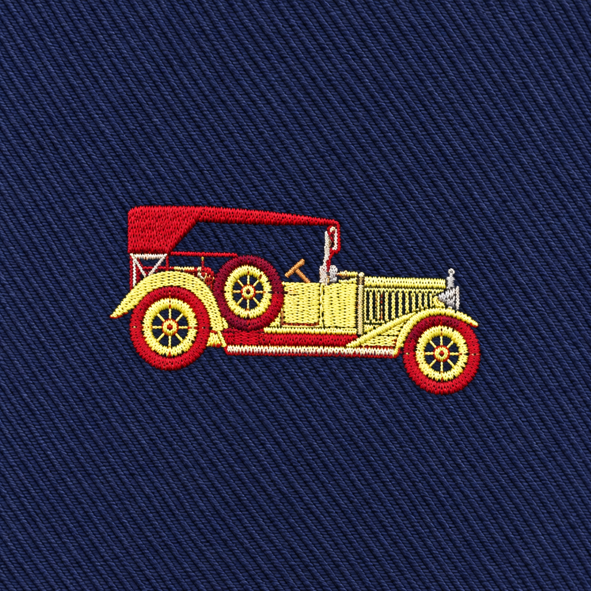 Add a touch of retro flair to your collection with the Classic Car Skinny Tie, featuring an embroidered vintage yellow car with a red roof and wheels on a dark blue fabric background—perfect for any novelty or classic car tie enthusiast.