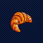 The Croissant Skinny Tie features an embroidered orange and brown croissant patch sewn onto a dark blue, diagonally striped fabric background, creating a whimsical French pastry-themed accessory—perfect for gourmet fashion or as a unique croissant tie.