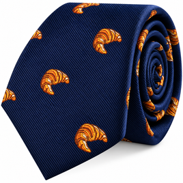The Croissant Skinny Tie in navy blue features an embroidered pattern of small orange croissants and comes rolled up neatly—a gourmet-inspired fashion accessory that brings playful charm to any outfit.