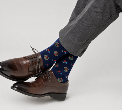 Someone wearing brown dress shoes, gray plaid trousers, and Darts Socks—blue novelty socks featuring dartboard and dart designs.