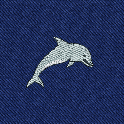 Showcase your style with the Dolphin Skinny Tie, featuring an embroidered gray dolphin on a textured blue fabric—perfect for anyone seeking unique, marine-inspired fashion accessories.