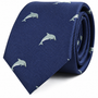 The Dolphin Skinny Tie is a rolled-up navy blue accessory featuring a pattern of small, light-colored dolphins—a marine-inspired tie perfect for anyone seeking unique fashion accessories.