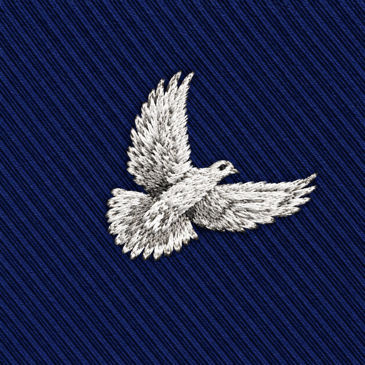 A white embroidered dove with outstretched wings graces the deep blue, diagonally-ribbed fabric of the Dove Skinny Tie, creating a timelessly elegant and symbolic accessory.