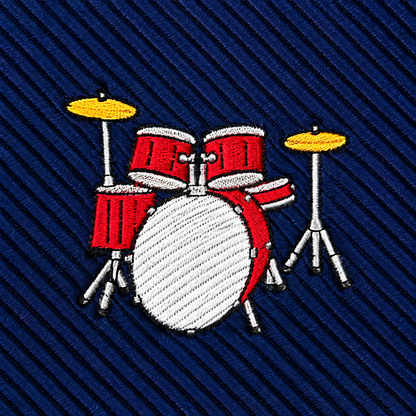 The Drums Skinny Tie features an embroidered red and white drum set with yellow cymbals on a blue, diagonally striped fabric background—an eye-catching percussion-themed accessory that’s the perfect gift for any music lover.