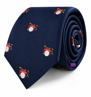 The Drums Skinny Tie features a navy blue background adorned with small red drum sets, displayed in a rolled position—making this percussion-themed accessory the perfect gift for any music lover.