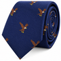 The Eagle Bird Skinny Tie is a blue slim-cut tie, rolled up for display, and features a repeating pattern of embroidered bald eagles in flight.