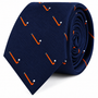 A coiled navy blue Field Hockey Skinny Tie featuring a repeating pattern of orange sticks and white balls.