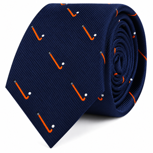 A coiled navy blue Field Hockey Skinny Tie featuring a repeating pattern of orange sticks and white balls.