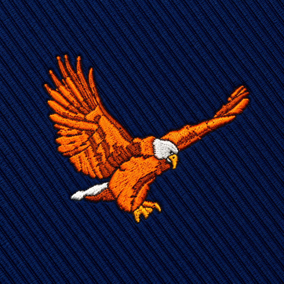 Flying Eagle Skinny Tie featuring an embroidered patch of a soaring orange eagle on a navy blue diagonal-ribbed fabric.