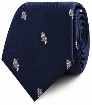 The Misty Cat Skinny Tie is a navy blue necktie with a subtle ribbed texture, adorned with a repeating pattern of small embroidered cats—an ideal pick for those seeking a playful alternative to a traditional tie.