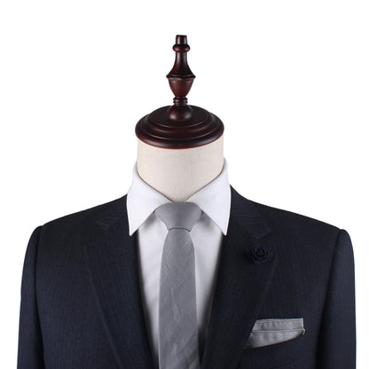 A display mannequin dressed in a dark suit with a white shirt, complemented by the Grey Cotton Skinny Tie & Pocket Square Set, showcases a versatile style combo perfect for any occasion.