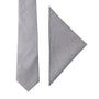 The Grey Cotton Skinny Tie & Pocket Square Set is displayed against a plain white background, showcasing the versatile light gray necktie alongside the neatly folded matching pocket square to create a stylish combination.