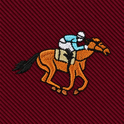 Add equestrian flair to your look with our Horse Racing Skinny MAROON Tie, featuring an embroidered patch of a jockey in blue and white riding a brown horse on a maroon diagonally-striped background—perfect for any horse racing enthusiast.