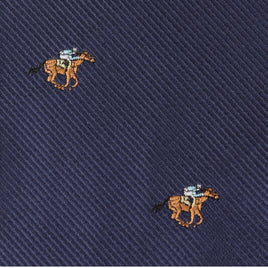 The Horse Racing Skinny Tie features navy blue fabric with small, embroidered brown horses and jockeys in blue shirts, arranged in a diagonal pattern—perfect for anyone who loves elegant equestrian style.