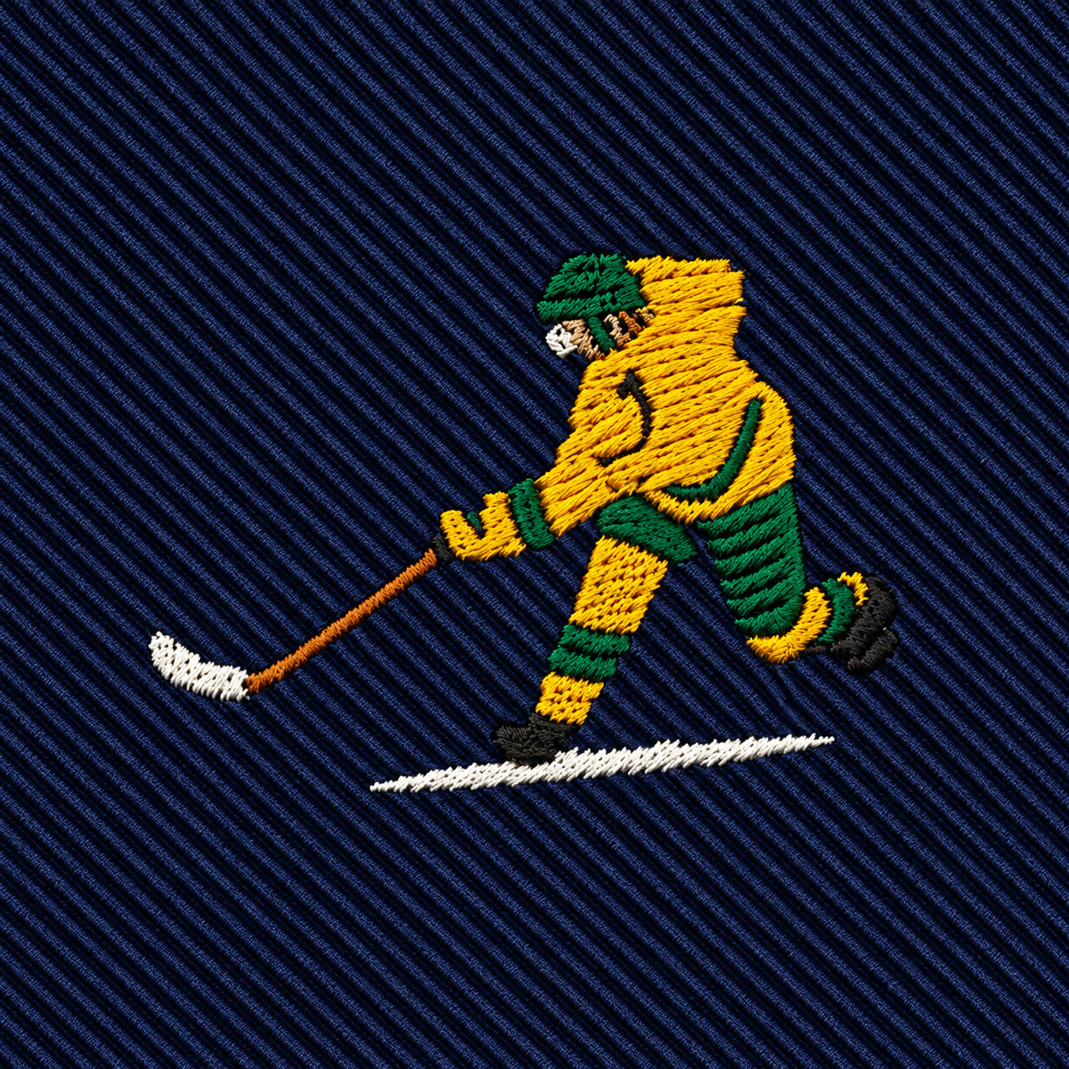 Ice Hockey Shot Skinny Tie featuring an embroidered patch of a hockey player in yellow and green gear hitting a puck on dark blue striped fabric—perfect as a unique gift for hockey lovers or a stylish addition to men’s hockey apparel.