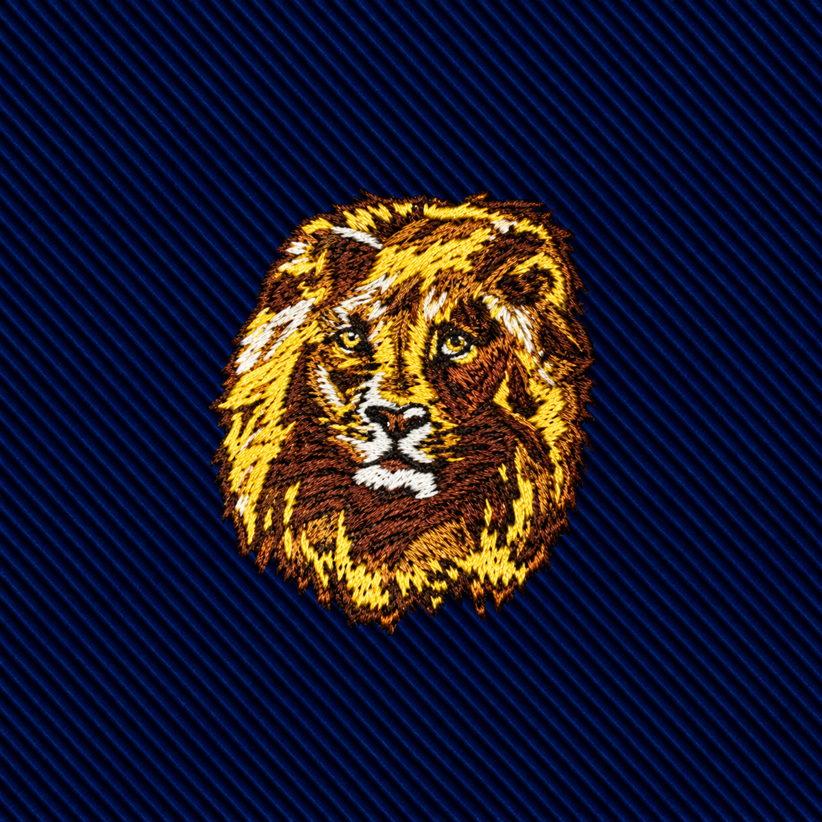 An embroidered gold lion head centered on a dark blue ribbed slim-cut King Lion Skinny Tie.