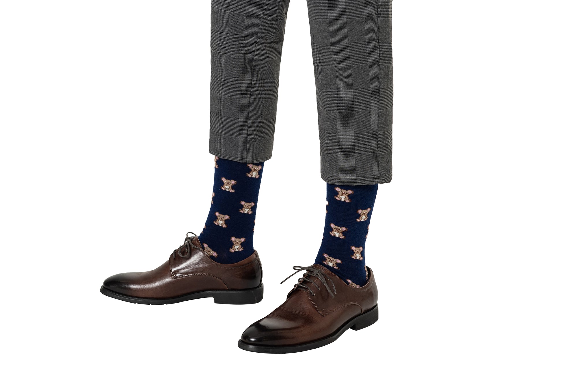 A person wearing gray plaid pants and brown dress shoes adds a delightful touch with blue Koala Socks featuring a playful teddy bear pattern.