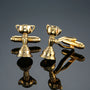The Melbourne Cup Horse Racing Trophy Cufflinks, gold-toned and trophy-shaped, are perfect for racing fans and displayed elegantly on a reflective black surface.