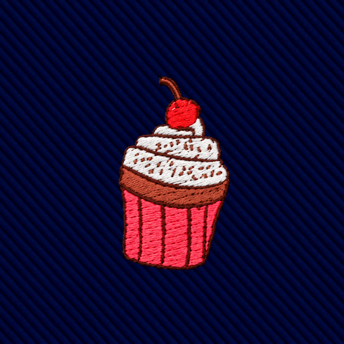 Muffin Skinny Tie featuring an embroidered cupcake patch with white frosting, chocolate drizzle, and a cherry on top, centered on a dark blue diagonal-striped bakery print tie.