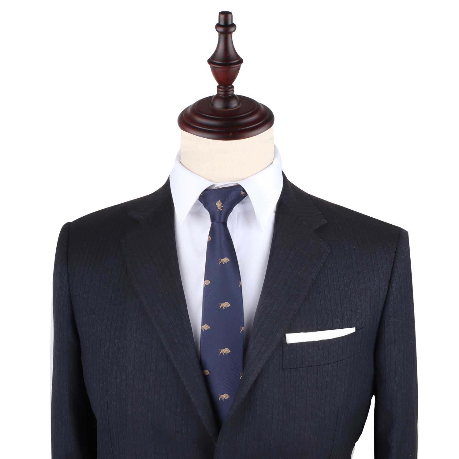 A tailored dark suit with a white pocket square and the Raging Bull Skinny Tie in navy featuring a subtle bull motif, displayed on a mannequin with a wooden top.