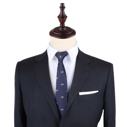 A tailored dark suit with a white pocket square and the Raging Bull Skinny Tie in navy featuring a subtle bull motif, displayed on a mannequin with a wooden top.