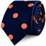 Rolled navy blue Orange Skinny Tie featuring a vibrant orange citrus slice pattern.
