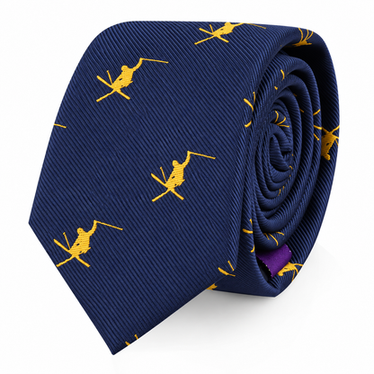 The Ski Tie features a navy blue background adorned with small yellow skiers, neatly rolled and presented on a white backdrop—making it the perfect winter-themed accessory and a thoughtful gift for any skiing enthusiast.