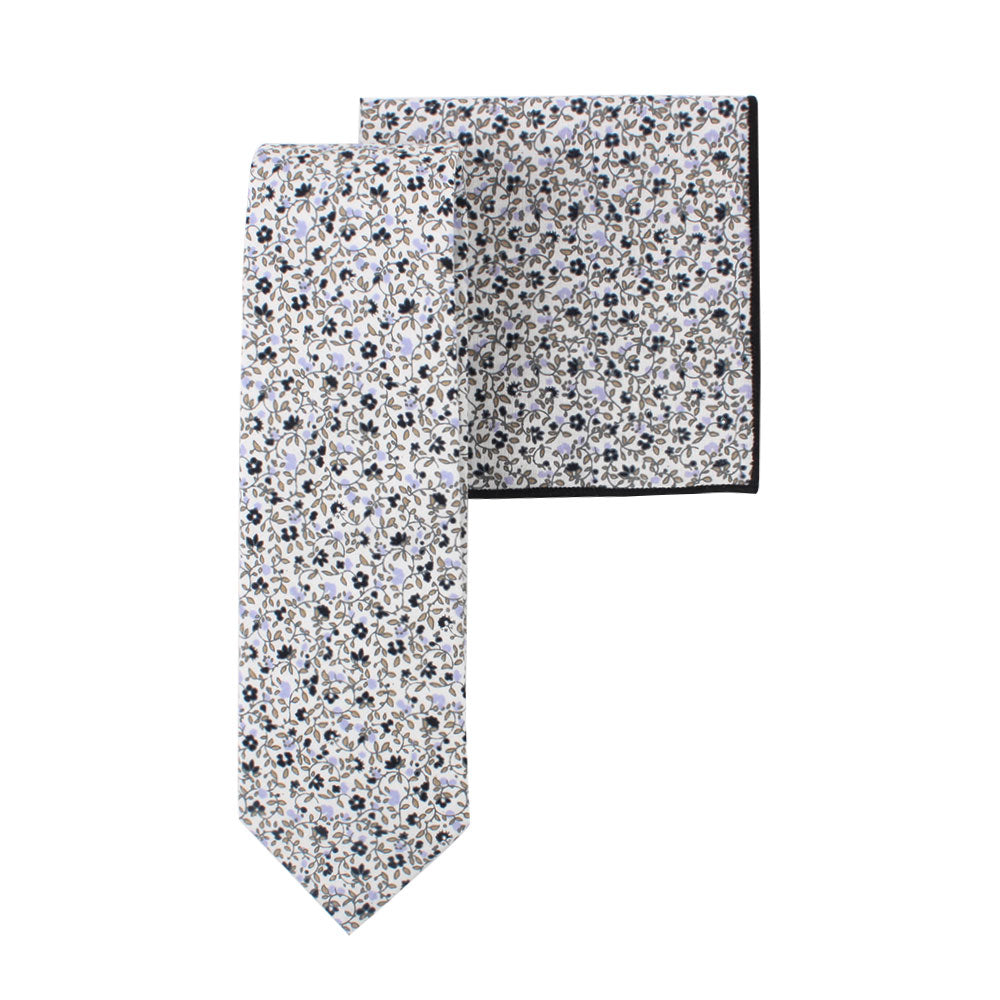 A Black Print Floral Cotton Skinny Tie & Pocket Square Set, predominantly white with small black and blue flowers, combines subtle florals with a sleek design.