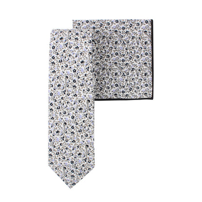 A Black Print Floral Cotton Skinny Tie & Pocket Square Set, predominantly white with small black and blue flowers, combines subtle florals with a sleek design.
